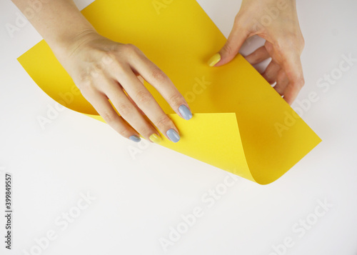 Hands with Yellow and gray manicure holding yellow paper.