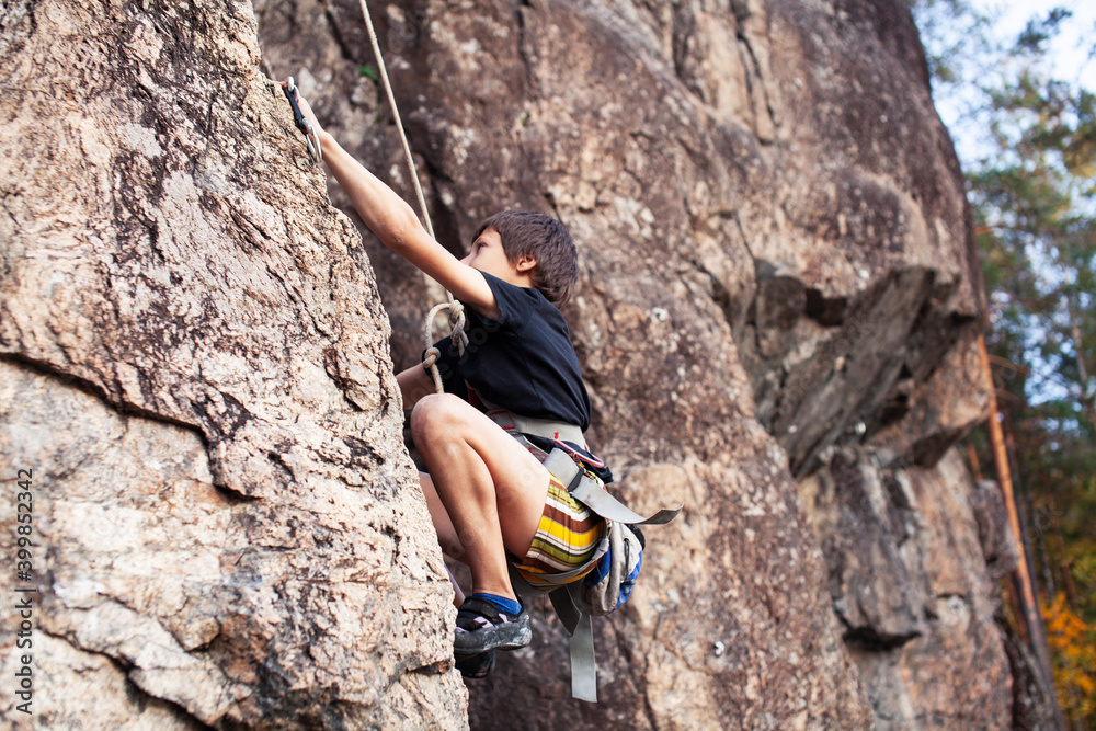 cute teen kid climbing on rock with insurance, lifestyle sport people concept cute teen kid climbing on rock with insurance, lifestyle sport people concept