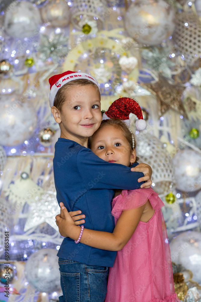 Portrait of two happy children siblings hugging each other by Christmas tree. Merry Christmas and happy holidays Portrait of two happy children siblings hugging each other by Christmas tree. Merry Christmas and happy holidays