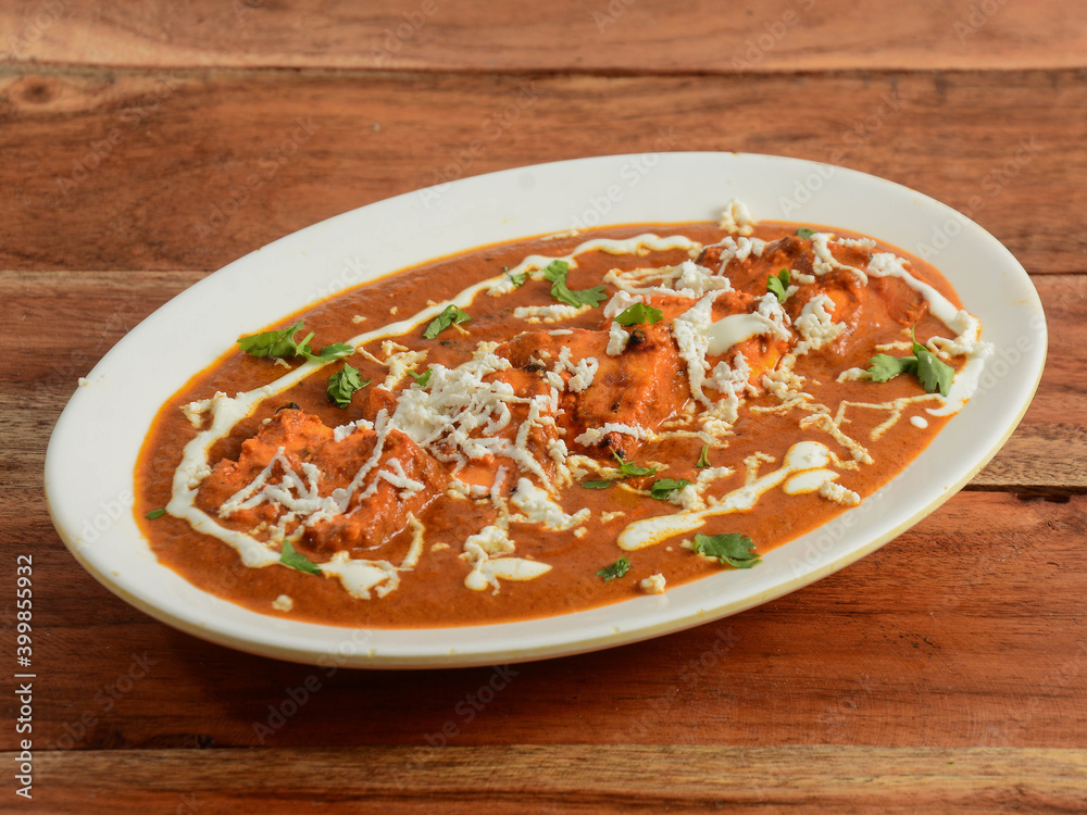 Paneer Tikka Masala is a famous indian dish, served over a rustic wooden background, selective focus Paneer Tikka Masala is a famous indian dish, served over a rustic wooden background, selective focus