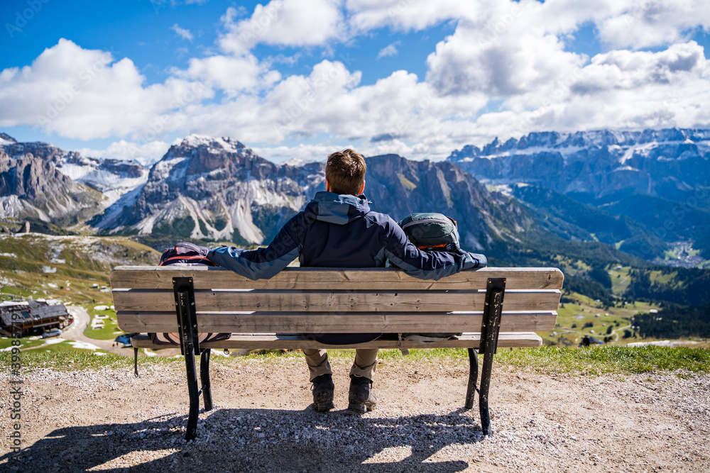 person sitting on a bench in the dolomites mountains person sitting on a bench in the dolomites mountains