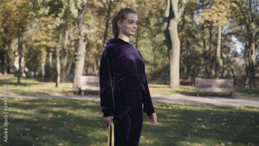 Confident gorgeous sportswoman measuring hips with tape standing on green meadow outdoors. Portrait of Caucasian woman enjoying sunny day after workout. Sport and beauty concept.