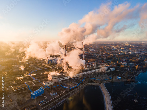 Factory chimneys producing smoke at sunrise, aerial view. Concept of air pollution, environment and ecology crisis, climate change, global warming