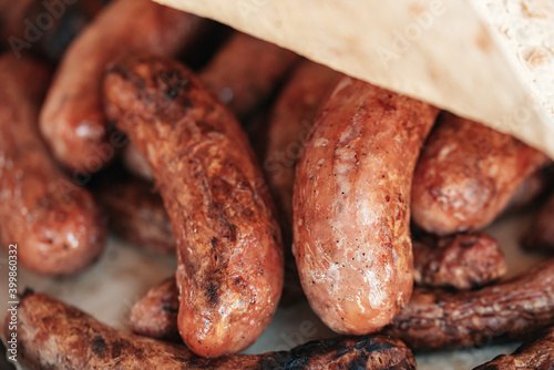 Grilled sausages or bratwurst on grill with smoke and flame. Delicious german sausages on barbecue grill. summer picnic, close up of grill, concept of resting in fresh air. BBQ in garden.