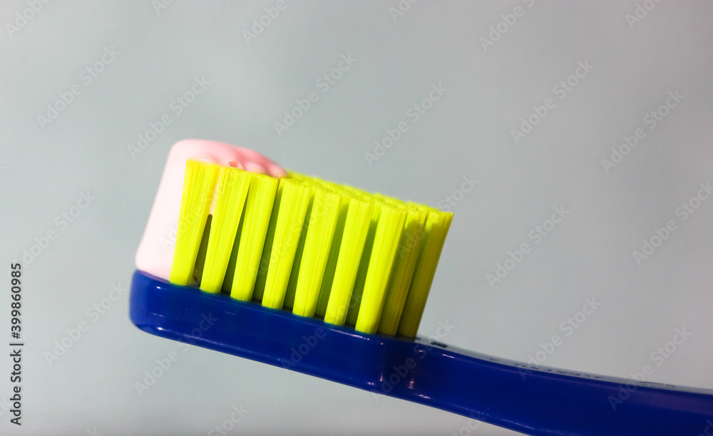 Blue toothbrush with green bristles close-up, pink toothpaste. Dental hygiene and care products from the dentist Blue toothbrush with green bristles close-up, pink toothpaste. Dental hygiene and care products from the dentist