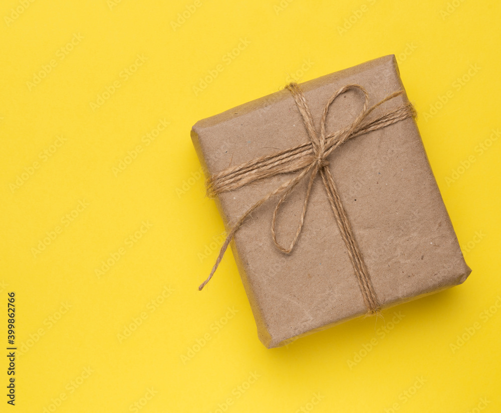 square box with a gift wrapped in brown paper and tied with a brown ro - obrazy, fototapety, plakaty 