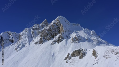 Mountain in winter - Drone turning around a snowy mountain in Tignes - Val d'Isère, with a blue sky in background