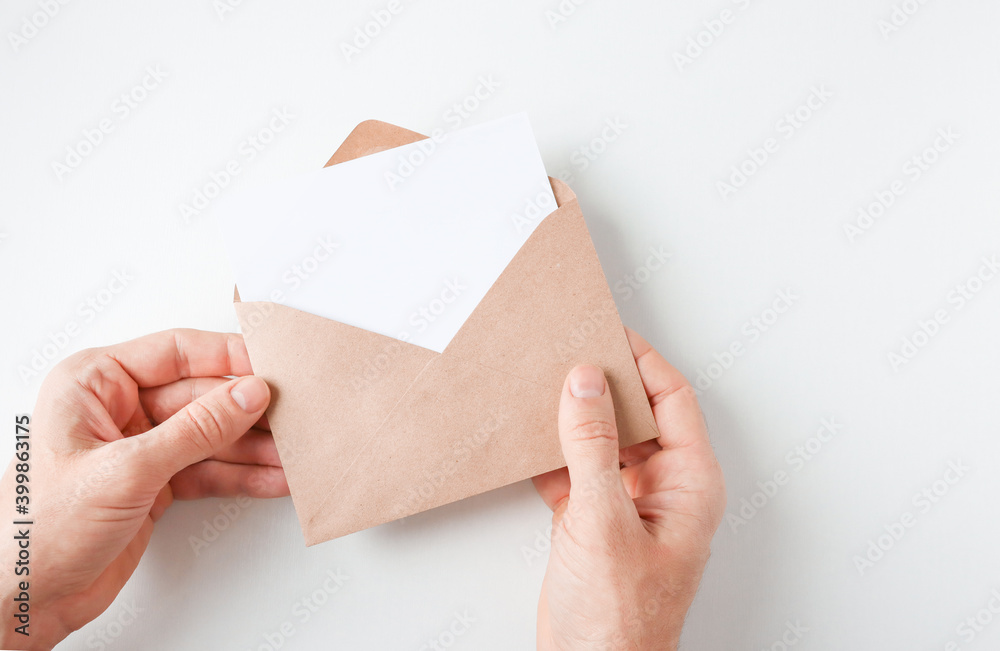 Fototapeta premium Men's hands hold the envelope. open envelope with white sheet copy space.