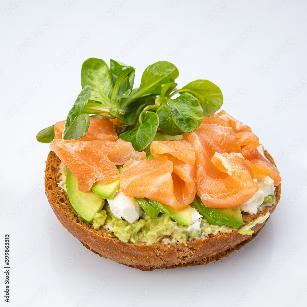 Bagel with salmon and herbs on a white background.
Bagel with salmon and herbs on a white background.