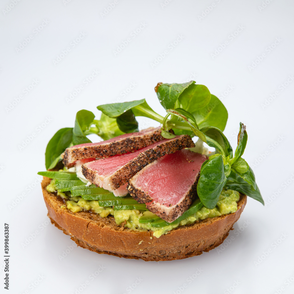 Bagel with tuna and greens on white background.
Bagel with tuna and greens on white background.