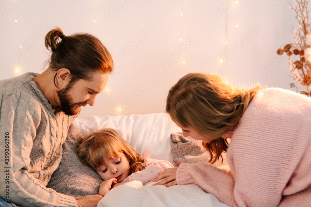 Parents kiss and caress their daughter who sleep in bed Parents kiss and caress their daughter who sleep in bed