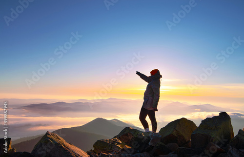 Girl on top of the mountain at sunrise.