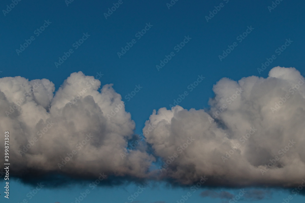 large white cumulus clouds with their bases shaded with gray, floating gently under a blue sky.