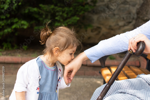 Little baby girl kiss her grandmother's hand during Eid mubarak (Turkish Ramazan or Seker Bayram). Adorable child kiss elderly woman hand to show respect. Cute toddler follow muslim Ramadan traditions