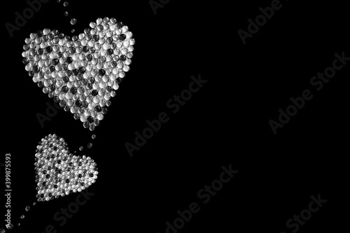 Two hearts made of stones isolated on black background. Black and white image. Poem background. Valentine's Day. Christmas. Copy space.