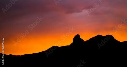 Vivid Sunset with Mountain Horizon Silhouette Rays of Light in Purple and Orange