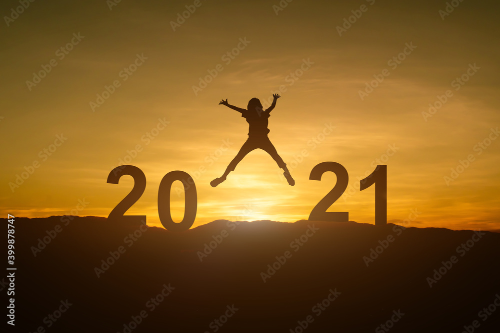 Silhouette of young woman jumping to Happy new year 2021 in sunset or sunrise background.