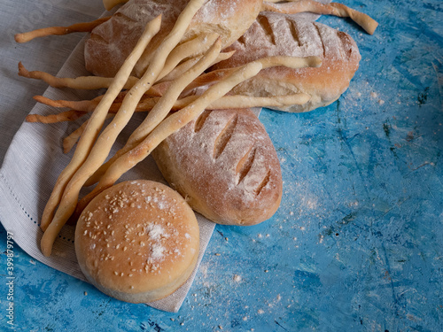 Italian gressini bread sticks and bread. Delicious aromatic pastries on a blue textured background.