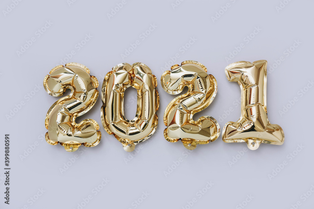 Foil balloons in the form of numbers 2021 on gray background. New year celebration. Foil balloons in the form of numbers 2021 on gray background. New year celebration.