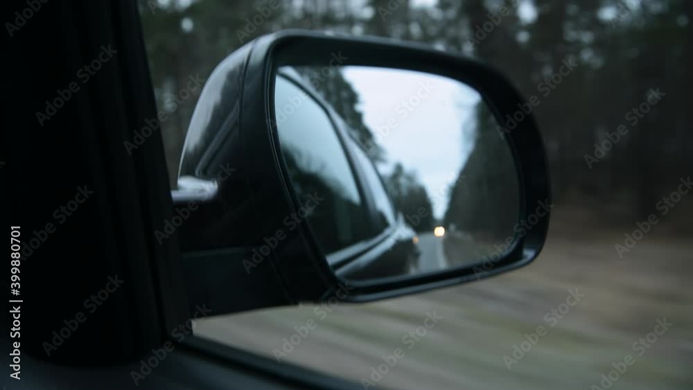 Close up rearview mirror of an SUV driving along the forest. Traveling on a cloudy day Close up rearview mirror of an SUV driving along the forest. Traveling on a cloudy day