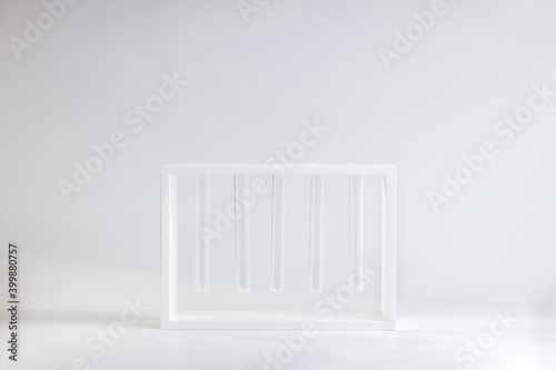 white flower vase made by glass test tubes stand over gray background. creative flowerpot