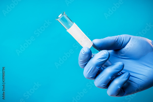 medical person or scientist holding glass test tube isolated over blue background. blank white label. copy space