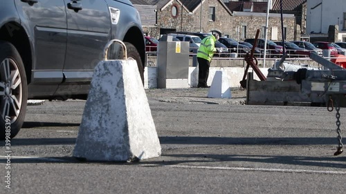 Workman in hi vis jacket cleaning wall at Le Croq car park on the side of St Sampson's Harbour Guernsey on sunny day photo