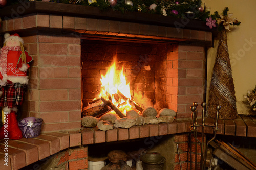 View of the fireplace with Christmas decorations and burning wood. 
