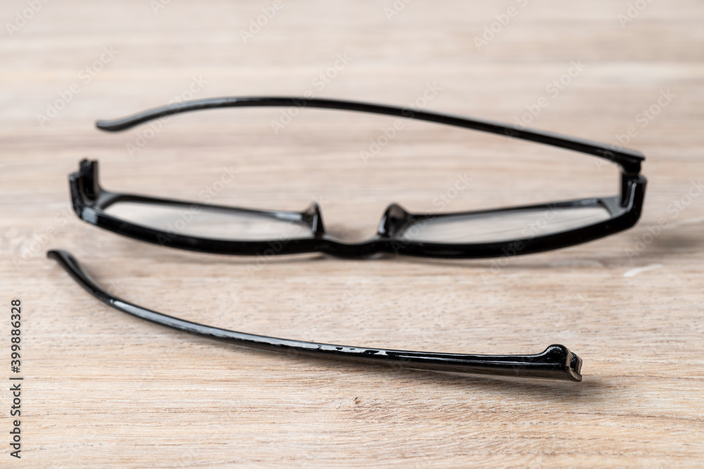 Foto de One eyeglasses temple in front of broken spectacles on a brown