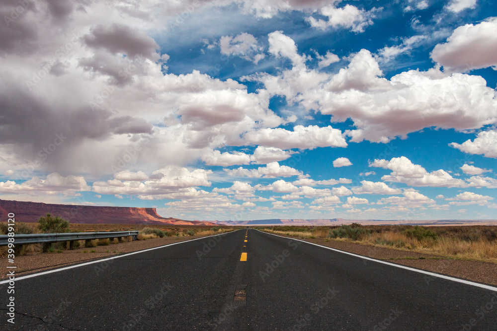 Empty road in the Arizona desert with big clouds and blue sky