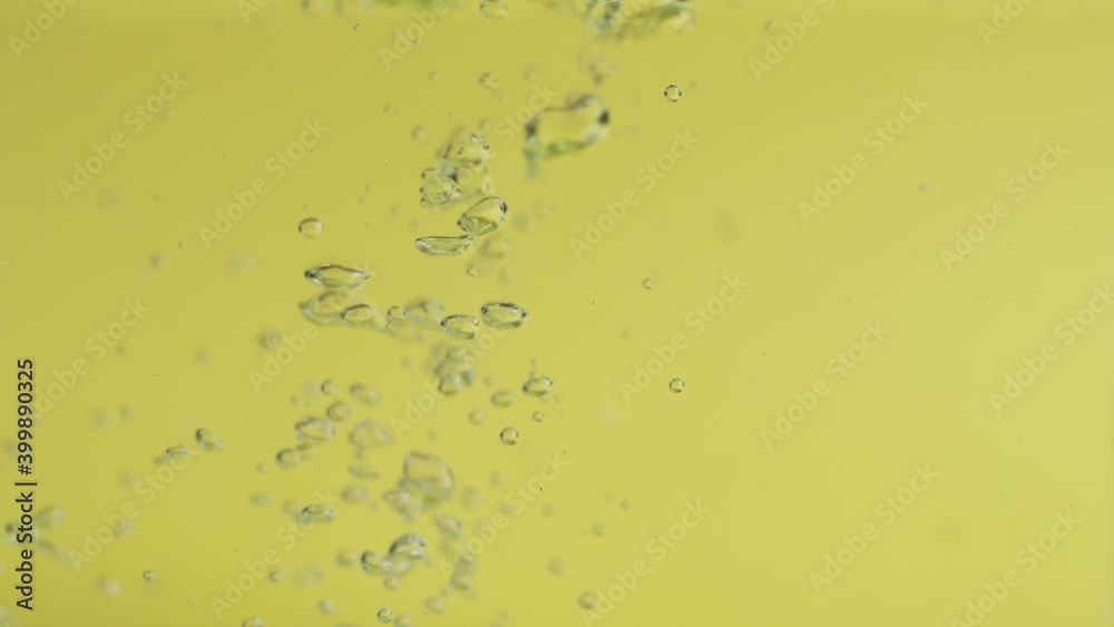 Clear Water With Bubbles Floating And Rising Beneath In Yellow Background - macro, slow motion Clear Water With Bubbles Floating And Rising Beneath In Yellow Background - macro, slow motion