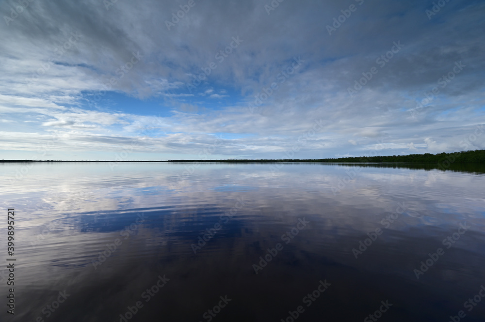 Winter cloudscape reflected in tranquil water of Coot Bay in Everglades National Park in late afternoon.