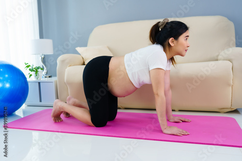 pregnant woman doing yoga exercise in living room at home
