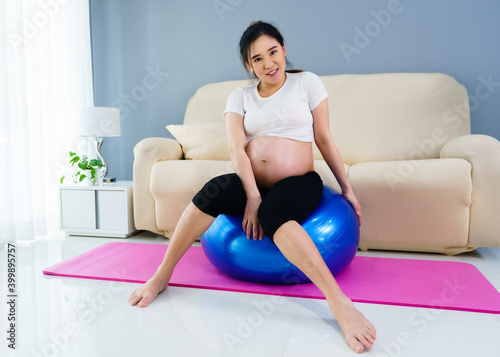 pregnant woman doing yoga exercise on fitness ball in living room at home