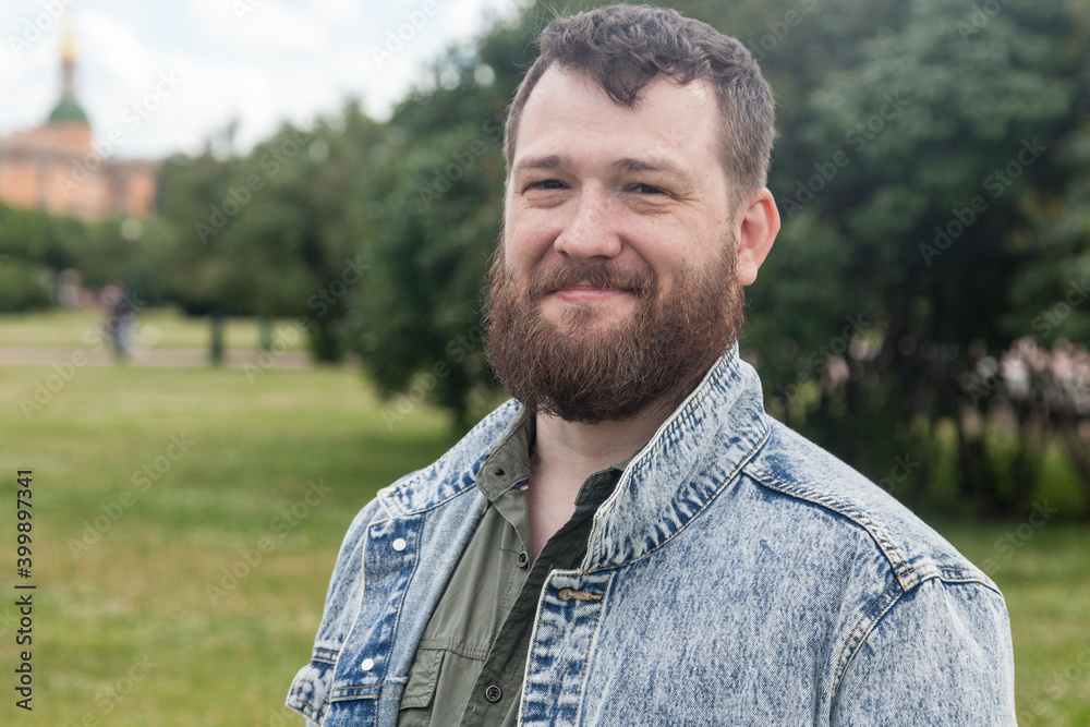 Bearded brown haired middle-aged man sitting in summer park Bearded brown haired middle-aged man sitting in summer park