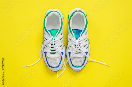 Top view of beautiful white stylish sneakers on a bright trendy yellow background