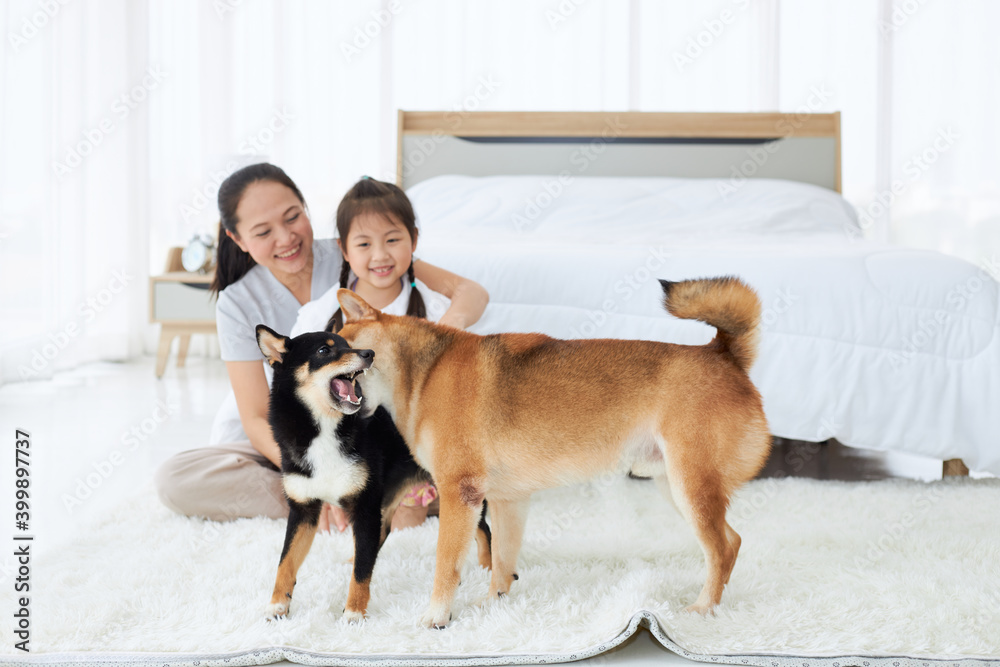 Asian mom and daughter with dog at bedroom.