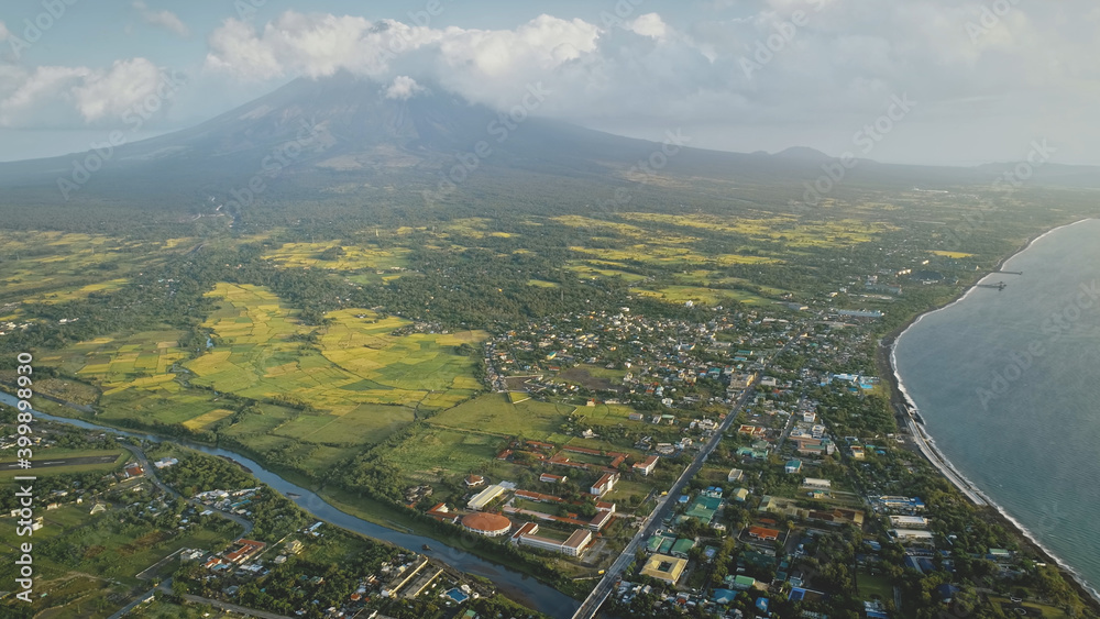 Tropic cityscape at sea bay river banks aerial. Streets with cottages and lodges with traffic road. Green valley at Mayon volcano Legazpi city, Philippines. Nobody nature landscape at mist haze