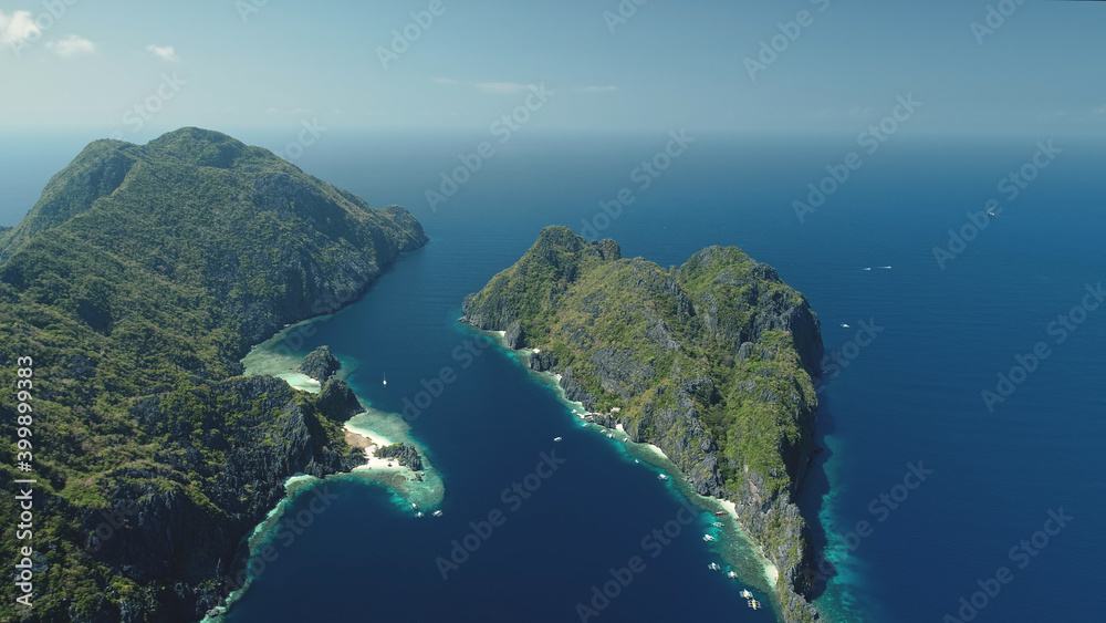 El Nido Islands at blue sea bay aerial view. Green mountain isles with tropical forest at sand beach. Wonderful seascape with greenery islets of Philippines Archipelago. Cinematic drone shot El Nido Islands at blue sea bay aerial view. Green mountain isles with tropical forest at sand beach. Wonderful seascape with greenery islets of Philippines Archipelago. Cinematic drone shot