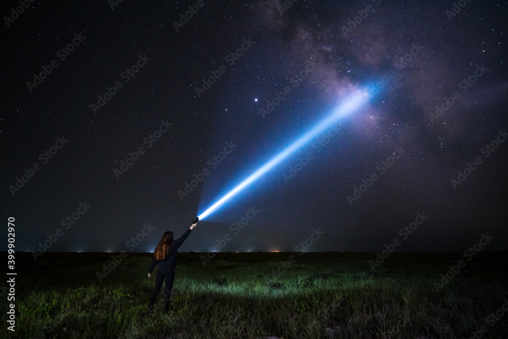 Young Woman illuminates the night sky and milky way with her flashlight Landscape Orientation