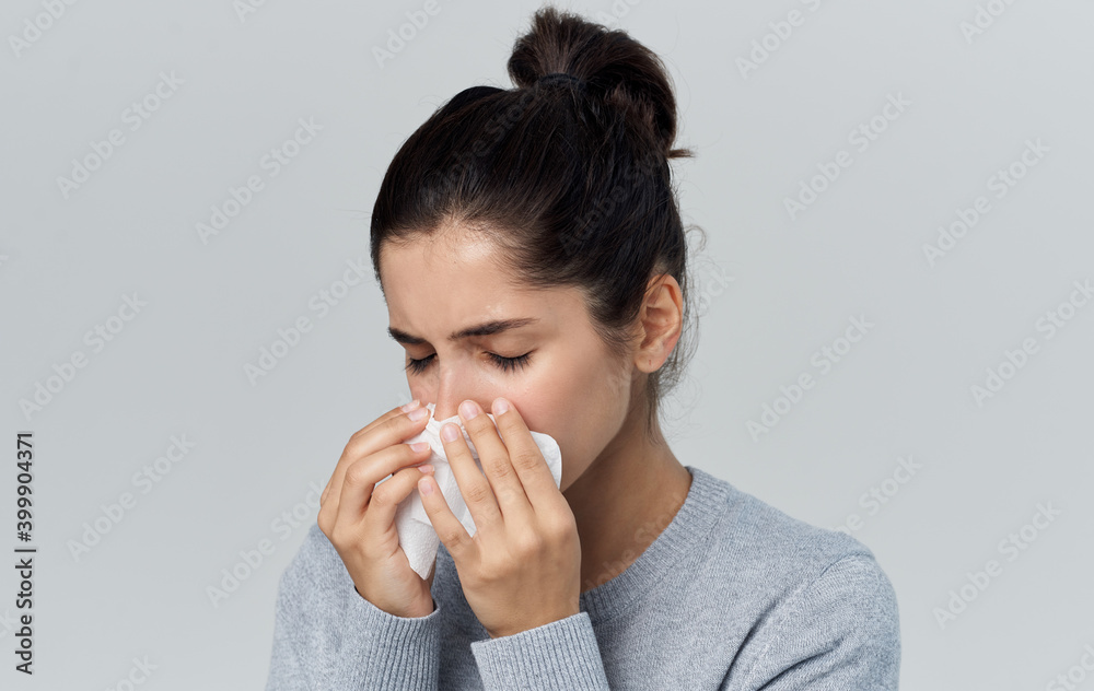 woman blows her nose into a napkin runny nose health problems gray background woman blows her nose into a napkin runny nose health problems gray background