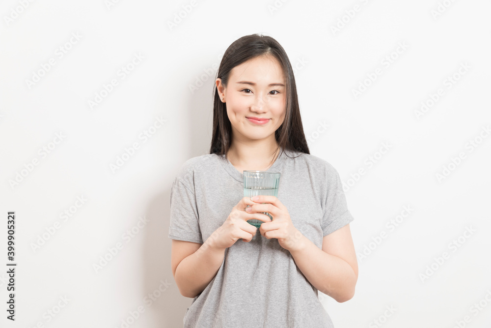Beautiful portrait young asian woman smiling drinking a glass of water mineral on white background. Beautiful portrait young asian woman smiling drinking a glass of water mineral on white background.