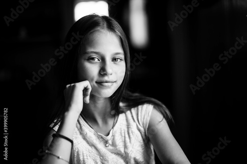 Portrait of teen girl sitting at the table. Black and white photo.