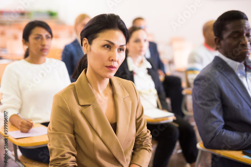 Young woman entrepreneur attending seminar with colleagues in board room