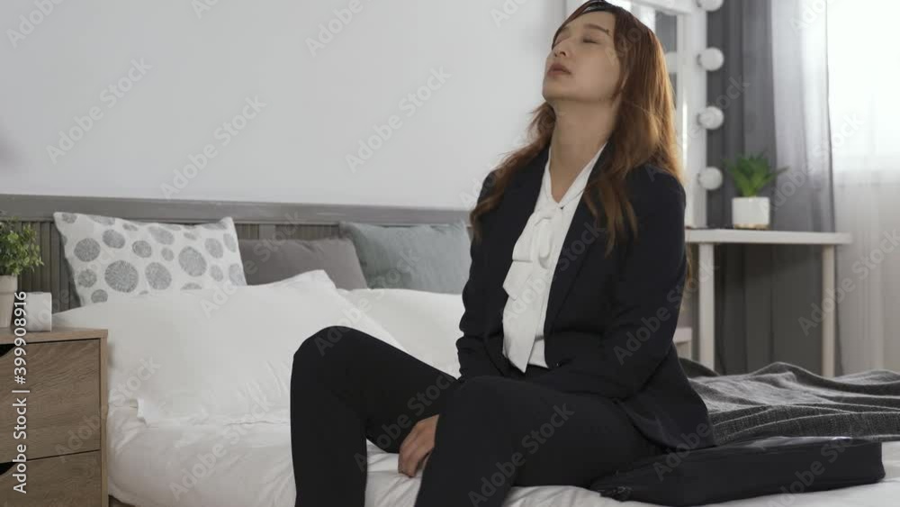 female entrepreneur slapping down her bag on bed, sitting at bedside and covering face in frustration. female entrepreneur slapping down her bag on bed, sitting at bedside and covering face in frustration.