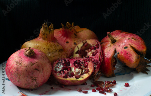 pomegranate whole and open-face on a white dish iin a light painting picture  photo