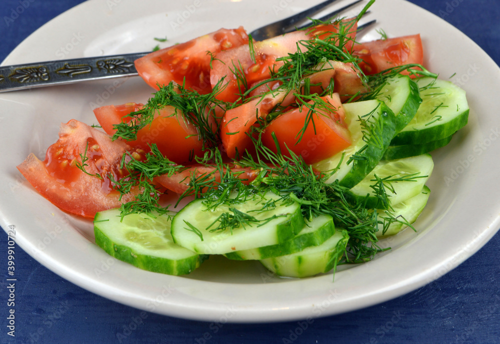 
a plate with cucumber and tomato salad is on the table