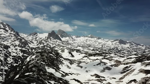 A drone shot of a snow-capped Alpine glacier and surrounding peaks in Schladming region, Austria. The slopes are partially covered with snow. Massive stony mountain. Many mountain chains in the back.
 photo