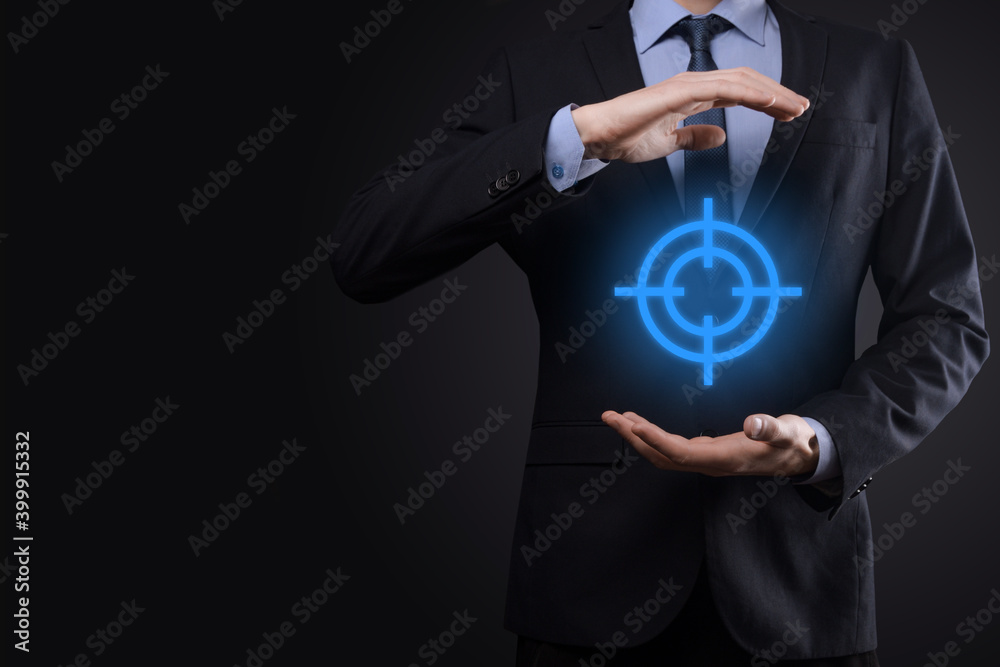 Targeting concept with businessman hand holding target icon dartboard sketch on chalkboard. Objective target and investment goal concept. Targeting concept with businessman hand holding target icon dartboard sketch on chalkboard. Objective target and investment goal concept.