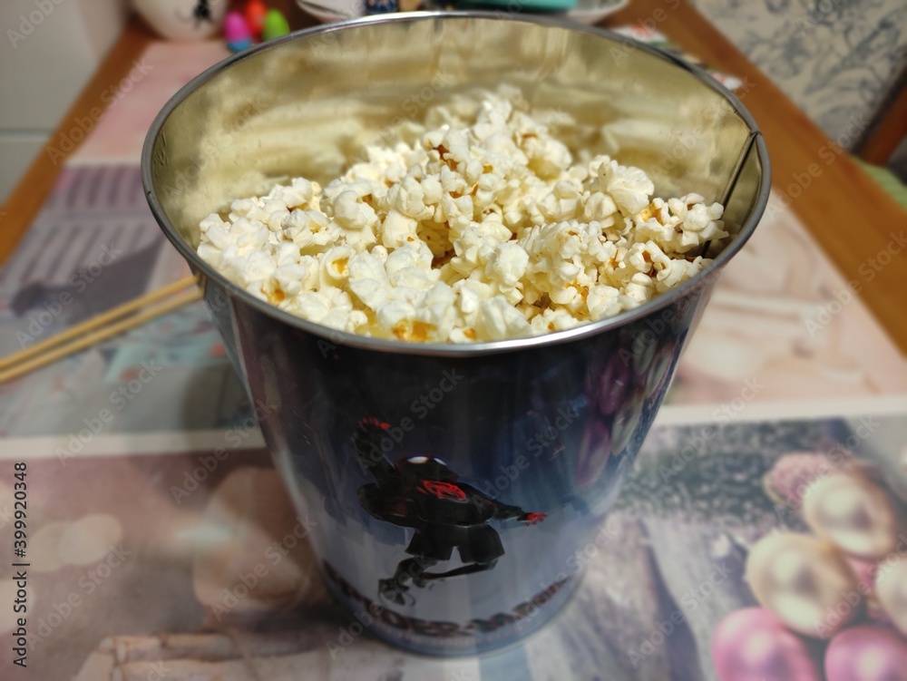 Naklejka premium Ready popcorn in an iron bucket with spiderman on the kitchen table.